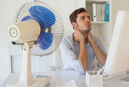 salarié qui a chaud au bureau avec un ventilateur